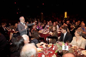 Donald Margulies (standing, left) toasts Gordon Edelstein (seated, right, in black jacket) at a tribute to the Long Wharf artistic director, held on the theater mainstage Oct. 3. Photo by T. Charles Erickson.